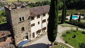 Un edificio in pietra con tetto in tegole, piscina e giardino curato.