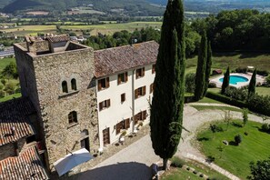 A stone building with a tiled roof, a swimming pool, and a well-maintained garden.