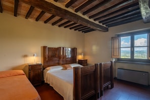 Un dormitorio con una cama de madera, una mesita de noche, una ventana con vistas y un radiador.