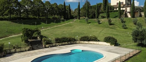 A swimming pool with a curved edge, surrounded by a paved deck.