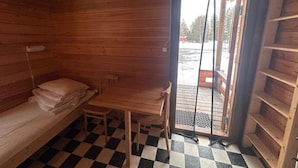 A cabin with a checkered floor, a bed, a table, and a door leading outside. - Skabram Camping & Stugby (Jokkmokk)