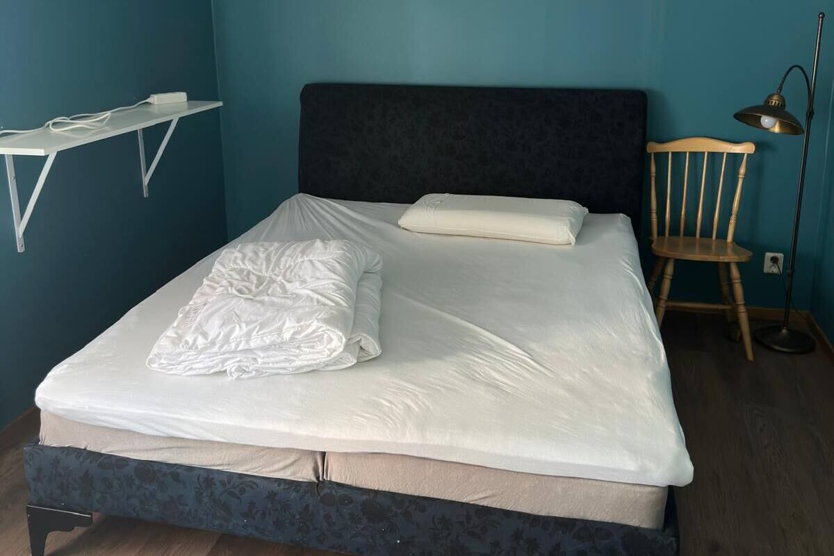 Ein Schlafzimmer mit Bett, Nachttisch, Stuhl und Stehlampe.