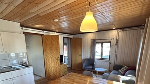 A wooden interior with a dining table, chairs, a kitchen area, and a sofa. - Skabram Camping & Stugby (Jokkmokk)