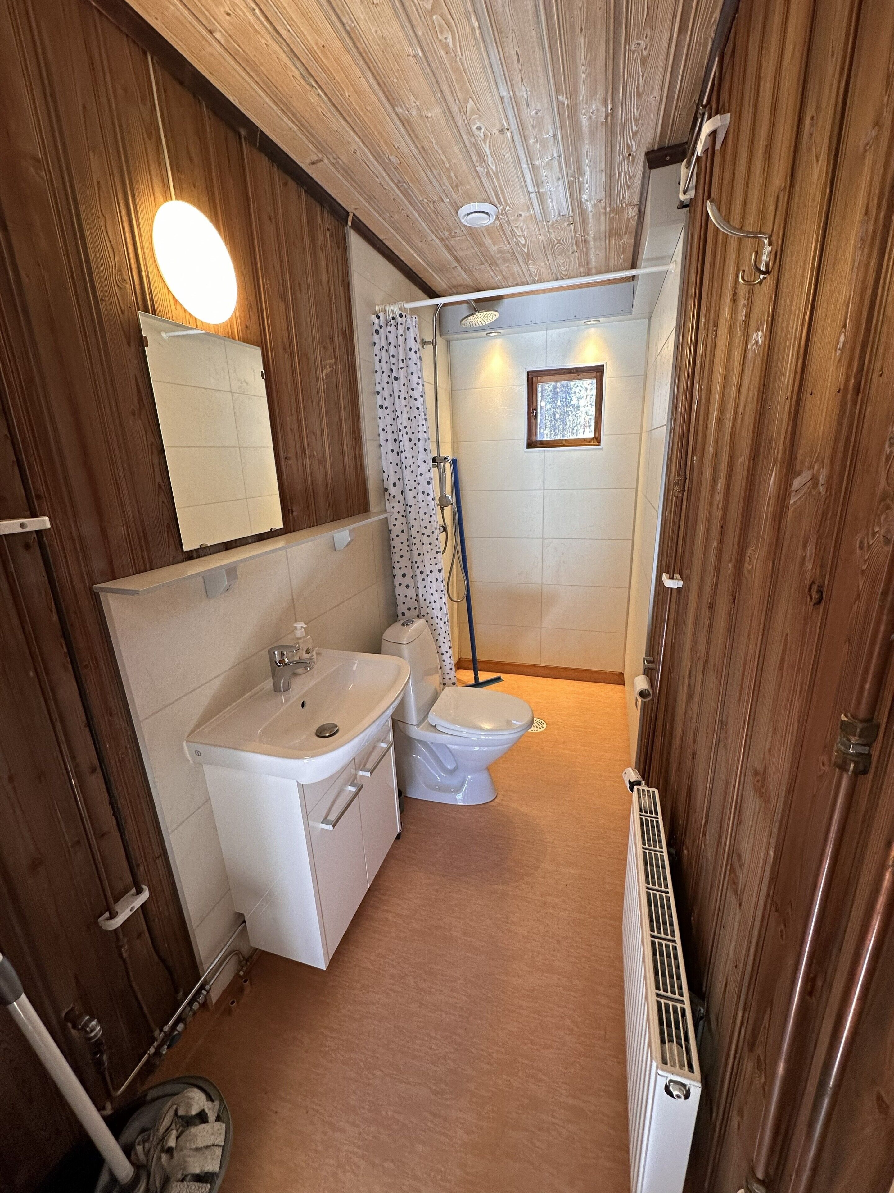 Een badkamer met douche, toilet en wastafel.
