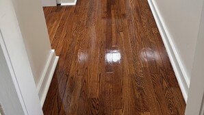 A hallway with wooden flooring and white walls.