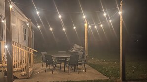 An outdoor patio with a table and chairs, string lights, and a covered area.