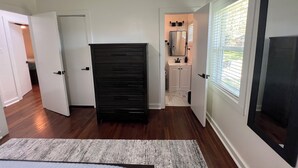 A hallway with a black storage unit, white walls, and a window with blinds.