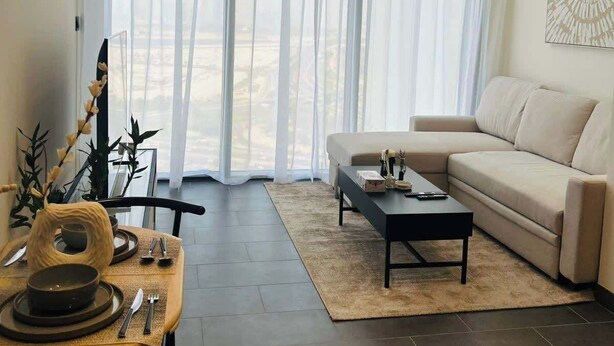 A modern living room with a sofa, coffee table, and dining area.