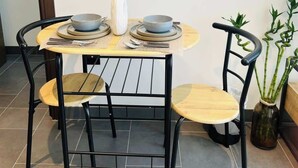 A dining table with four chairs, a vase with a branch, and a potted plant.