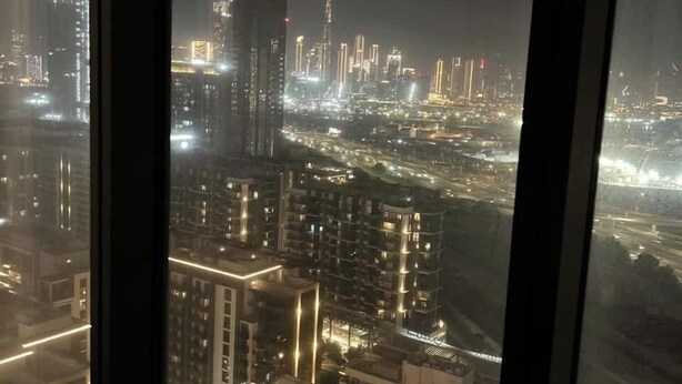 A nighttime cityscape viewed from a high-rise building with illuminated windows and a view of the skyline. - Burj Khalifa Views & Lagoonfront Luxury Apartment (Dubai)