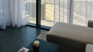 A modern living room with a large window offering a city view. - Burj Khalifa Views & Lagoonfront Luxury Apartment (Dubai)