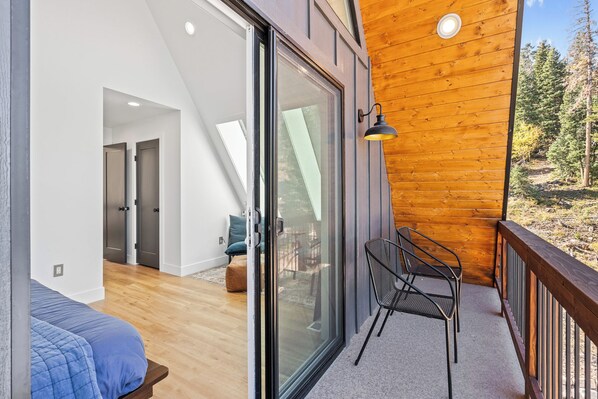A modern interior with a wooden deck, a glass sliding door leading to a balcony, and a cozy seating area.