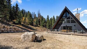 A modern building with a triangular roof, large windows, and a stone chimney. - Sleeps 15, Stunning A-Frame Retreat with Jaw Dropping Views (Mount Pleasant)