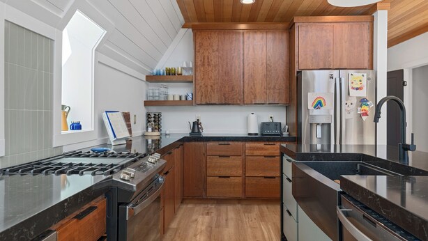 A modern kitchen with wooden cabinets, a stainless steel refrigerator, and a black countertop. - Sleeps 15, Stunning A-Frame Retreat with Jaw Dropping Views (Mount Pleasant)