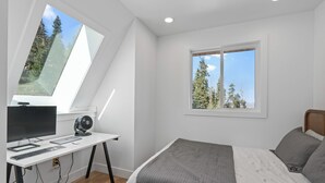 A bedroom with a bed, a desk with a computer, and a window with a view of trees. - Sleeps 15, Stunning A-Frame Retreat with Jaw Dropping Views (Mount Pleasant)