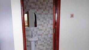 A bathroom with a tiled floor, a sink, and a mirror. - AYEBA ZION HOTEL (Fort Portal)