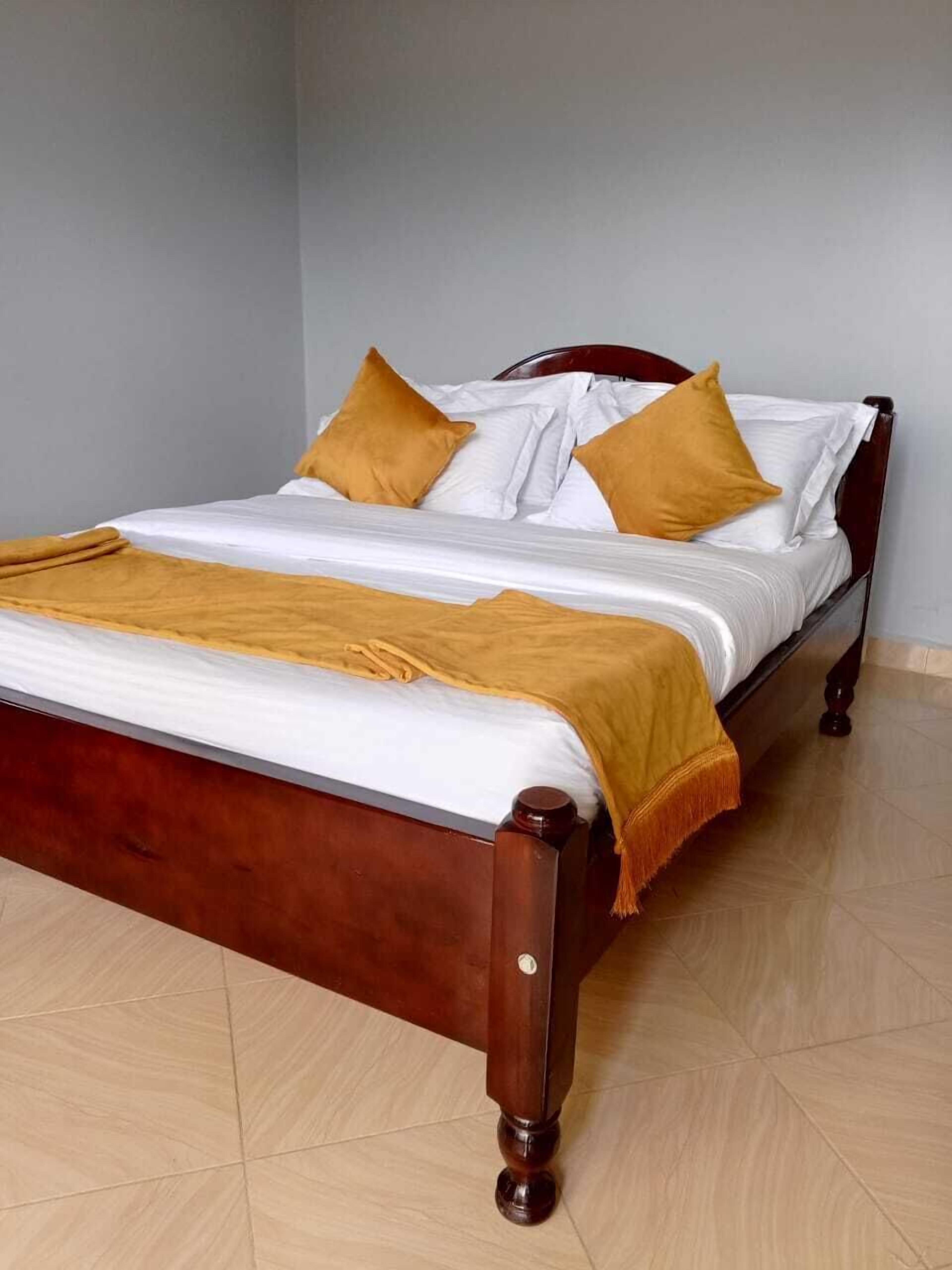 A bed with a wooden frame, white bedding, and two yellow pillows.