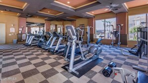 Ein Fitnessstudio mit mehreren Laufbändern, Kraftgeräten und einem großen Fenster mit Blick nach draußen.