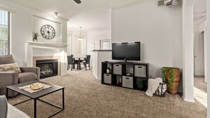 Ein Wohnzimmer mit Kamin, Fernseher und Deckenventilator.