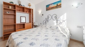 A bedroom with a bed, wooden shelving unit, a painting, and a decorative metal headboard. - Vacation House a few steps from the sea, Sant'Antioco  (SU)