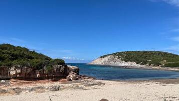 En strand med en klippe og en klar blå himmel.