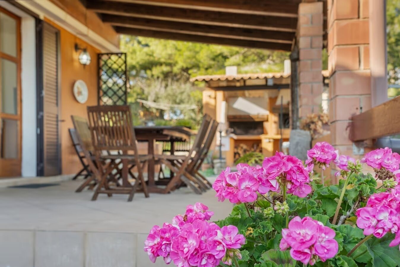 Une terrasse extérieure avec des meubles en bois et un mur en briques.