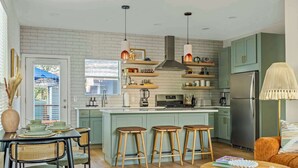 Una cocina moderna con una isla central, taburetes de bar e iluminación colgante.