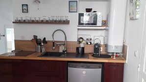 Cozinha compacta com lava-louças, micro-ondas e pia. Há prateleiras acima do balcão com potes de vidro e um micro-ondas.
