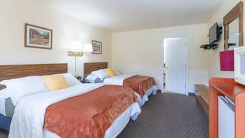 A hotel room with two beds, a desk, a TV, and a door leading to another room.