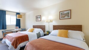 A hotel room with two beds, a desk, a chair, a lamp, and two wall-mounted lamps.
