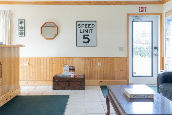 A room with a speed limit sign, a wooden cabinet, a suitcase, and a door with an exit sign.