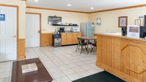 A compact kitchen with wooden cabinets, a microwave, a refrigerator, and a coffee maker.