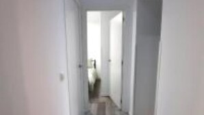 A narrow hallway with white walls and a wooden floor.