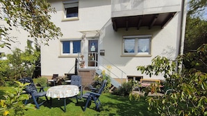 A residential building with a small patio area featuring a table and chairs, surrounded by greenery. - Vacation apartment in the countryside near Ulm in the "small Lautertal" - with garden (Blaustein)