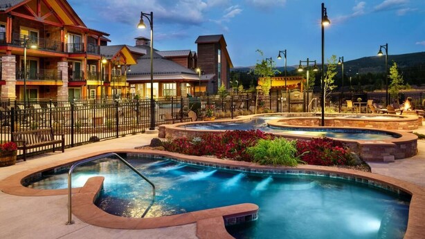 A hotel with a pool area, outdoor seating, and a well-lit entrance.