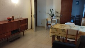A compact living space with a dining area, a small kitchen, and a doorway leading to another room.