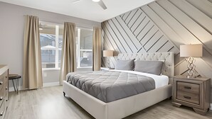 A modern bedroom with a bed, bedside tables, a desk, and a ceiling fan.