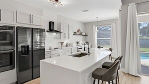A modern kitchen with a central island, stainless steel appliances, and a view to the outdoors.