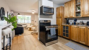 A compact kitchen with a built-in oven, microwave, and wooden cabinets. - Comfort & Style Modern | 2BR In West Palm Beach (West Palm Beach)