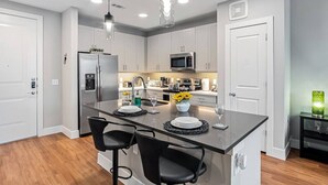 A modern kitchen with a central island, stainless steel appliances, and pendant lighting. - Cozy Luxury 1bd | Pool+Gym+Stockyards+Free Parking (Fort Worth)