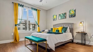 A bedroom with a bed, bench, bedside table, and artwork on the wall. - Cozy Luxury 1bd | Pool+Gym+Stockyards+Free Parking (Fort Worth)