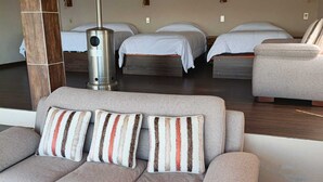 Une chambre d’hôtel moderne équipée d’un canapé, de deux lits, d’un radiateur et d’une table basse en verre.