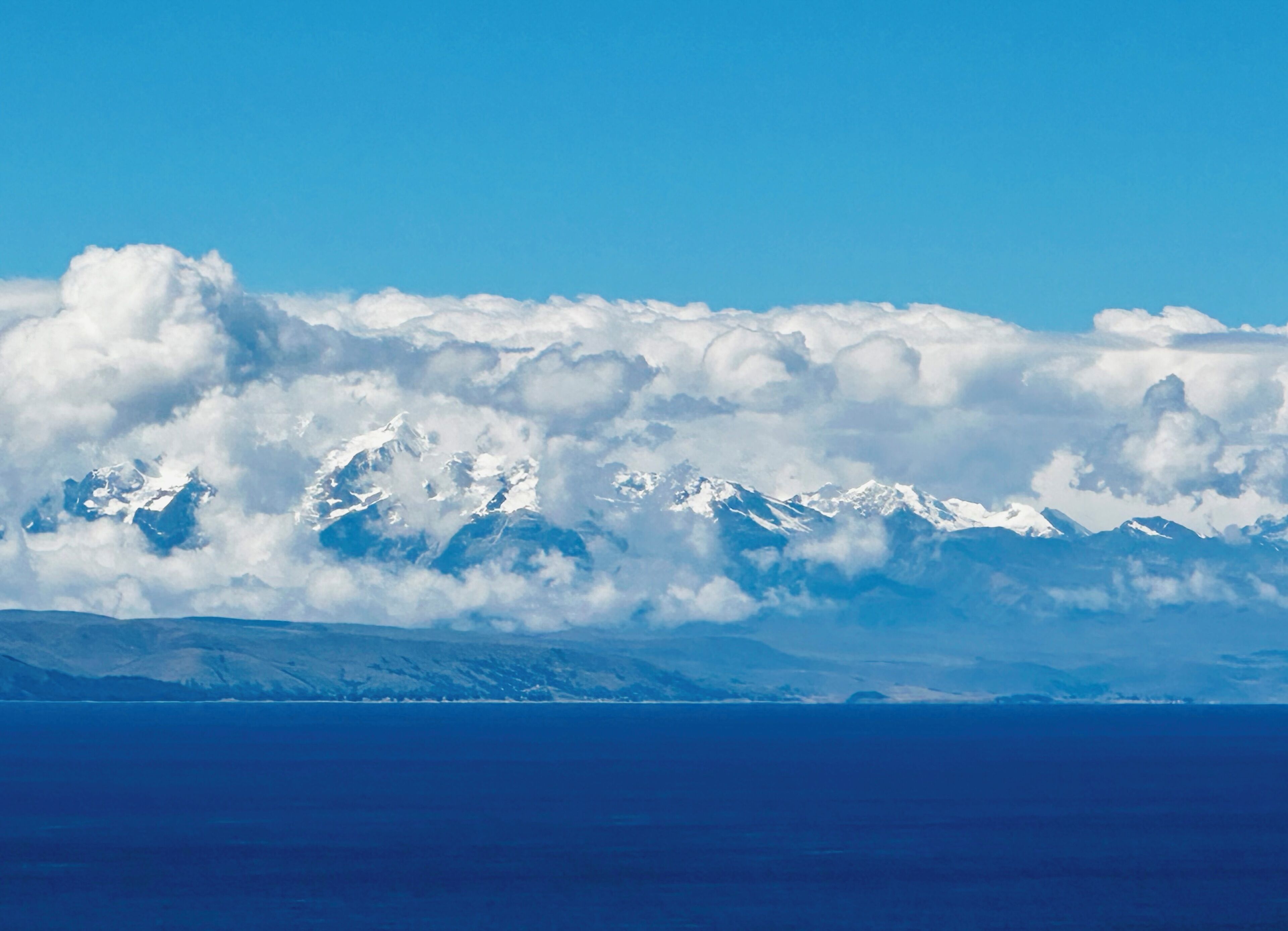 A mountain range with snow-capped peaks and a clear blue sky.