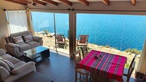 Un salon moderne comprenant un canapé, une table basse et une table à manger avec des chaises, offrant une vue panoramique sur la côte.