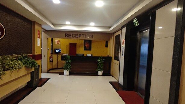 A reception area with a reception desk, a television, and potted plants.