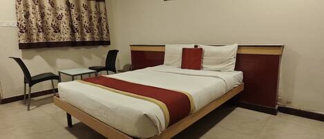 A bedroom with a bed, a desk, and two chairs.