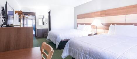 Una habitación de hotel con dos camas, un escritorio con silla y un televisor.
