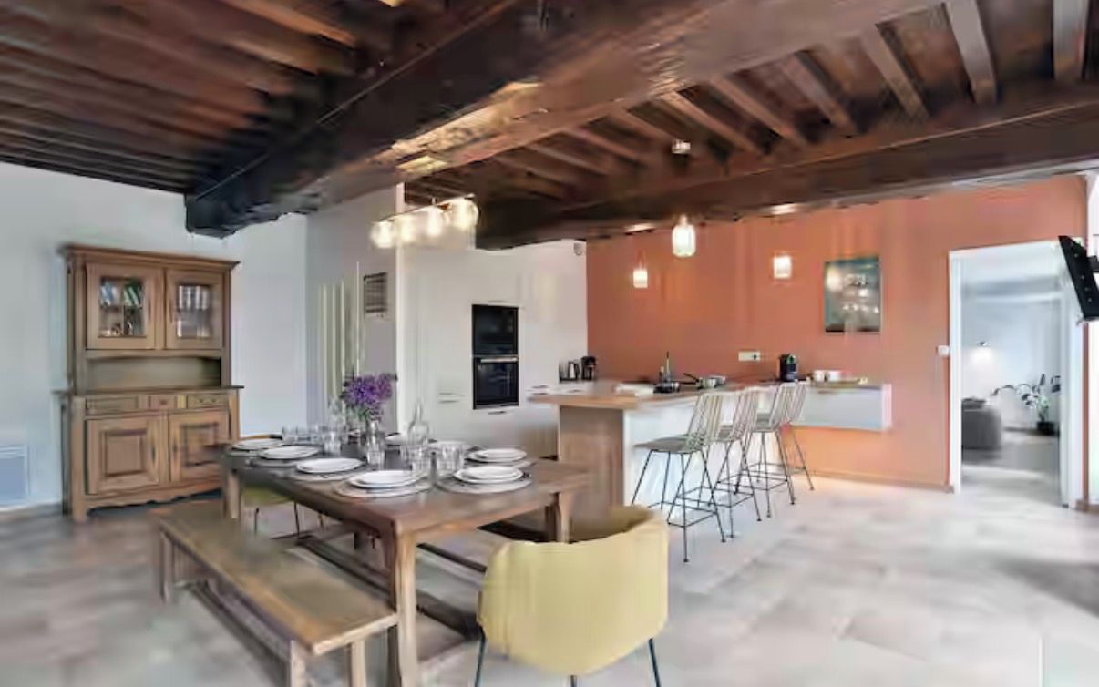 A spacious dining area with a wooden table set for four, a bench, and a yellow chair.