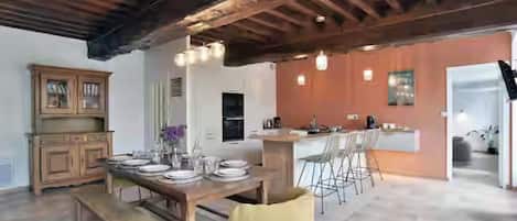 Un comedor amplio con una mesa de madera dispuesta para cuatro, un banco y una silla amarilla.