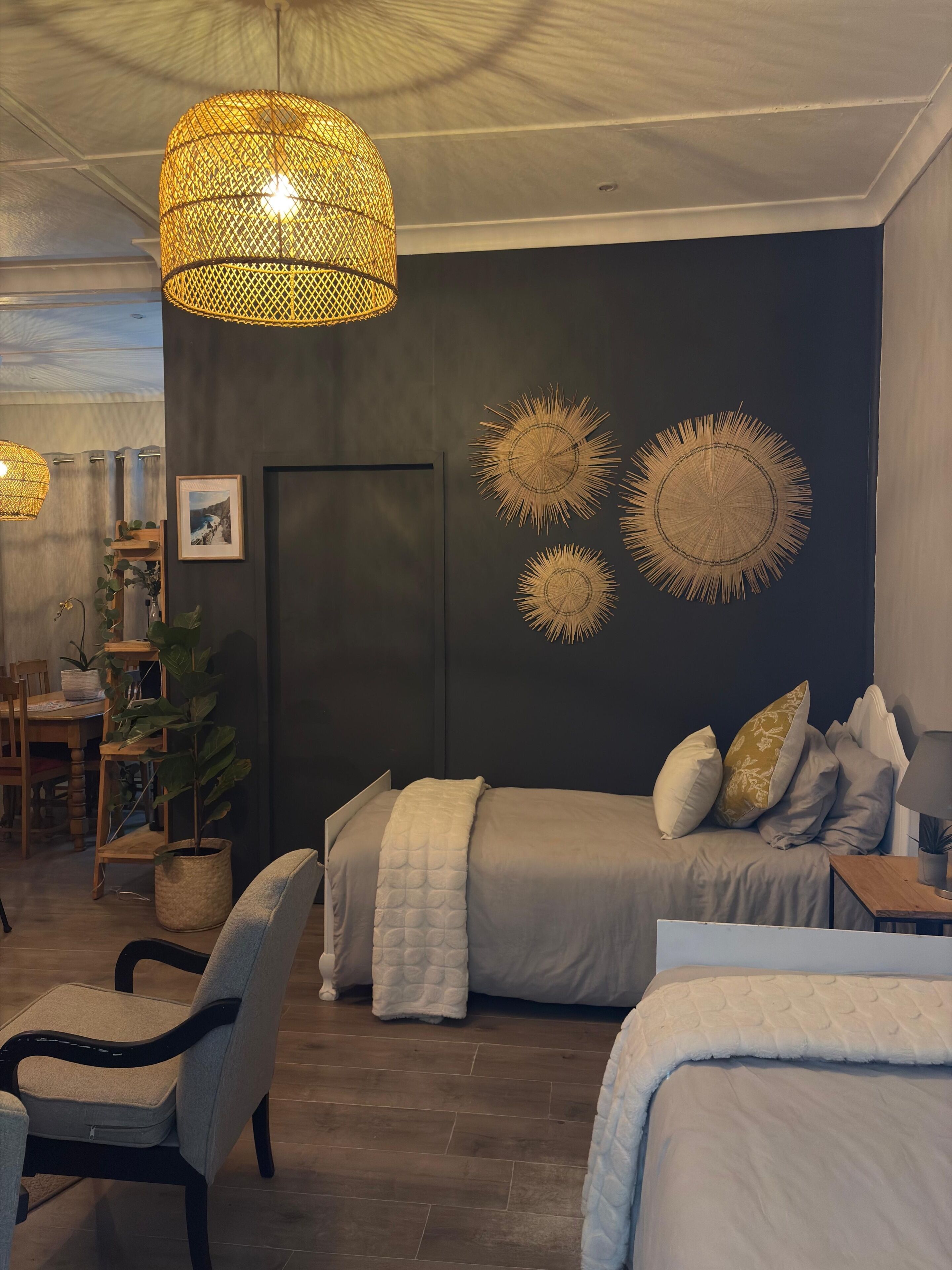 Une chambre à coucher comprenant un lit, des tables de chevet, une chaise, un bureau et un mur décoré.